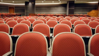 A multi-function auditorium with upholstered seats in rows clipart