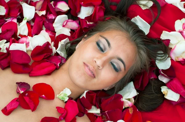 Slapende meisje in roos bloemblad Rechtenvrije Stockfoto's