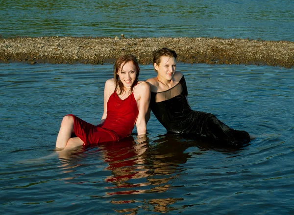 Meninas em vestido molhado senta-se na água — Fotografia de Stock