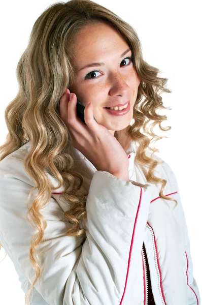 Улыбающаяся девушка в белой куртке с сотовым телефоном — стоковое фото