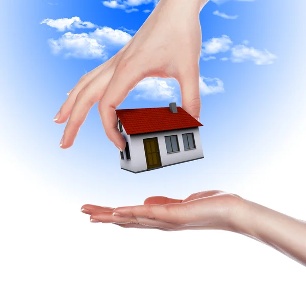 Huis in de handen tegen de blauwe hemel — Stockfoto