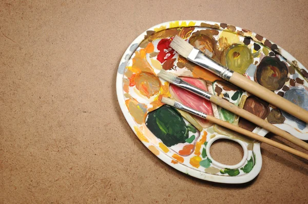 Dirty palette with paintbrushes on the cardboard paper — Stock Photo, Image
