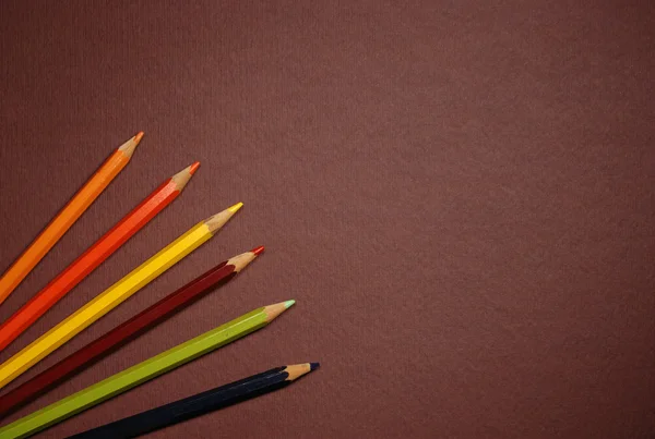 Empty brown cardboard background and coloured pencils — Stock Photo, Image