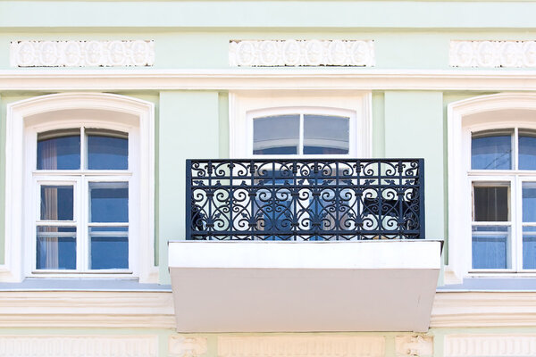 Windows and balcony with grate on wall of ancient building, Russia.