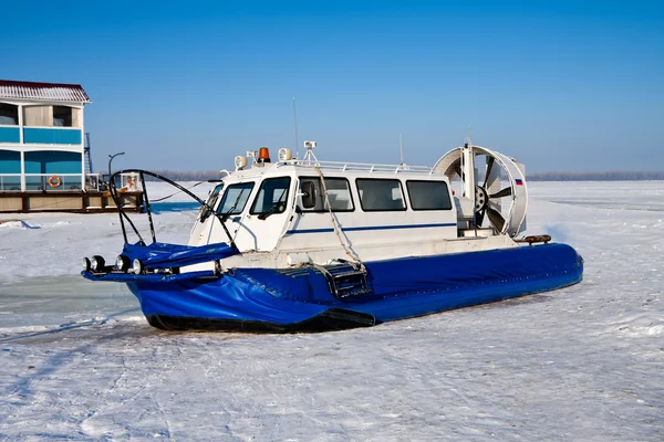 Hovercraft cruzando rio congelado contra um céu azul — Fotografia de Stock