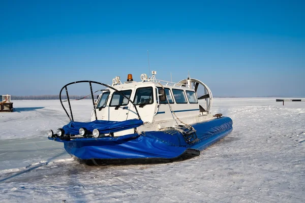 气垫船在冰封的河流对蓝蓝的天空的银行 — 图库照片