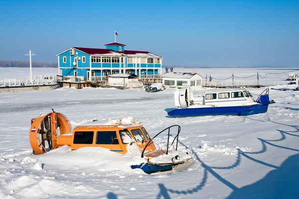 Luftkissenboot am Ufer des zugefrorenen Flusses vor blauem Himmel — Stockfoto
