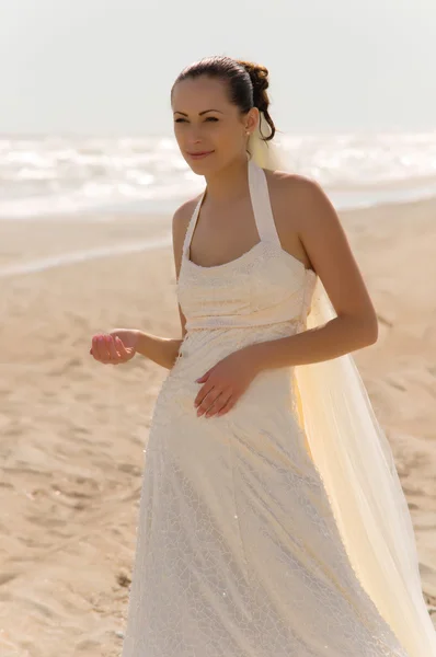 Jeune mariée se tient sur la plage — Photo