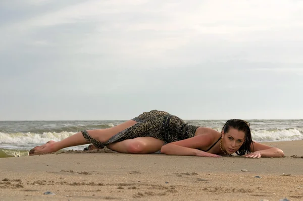 Vrouw liggend op het zand in een jurk — Stockfoto