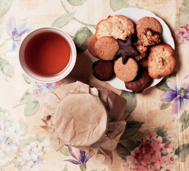 Tea with honey and cookies on flowers pattern, top view clipart