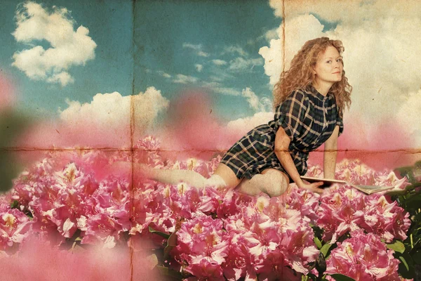 Skönhet ung kvinna lie i rosa blommor med bok — Stockfoto