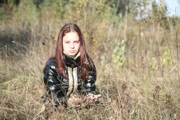 A menina-adolescente senta-se em um prado — Fotografia de Stock