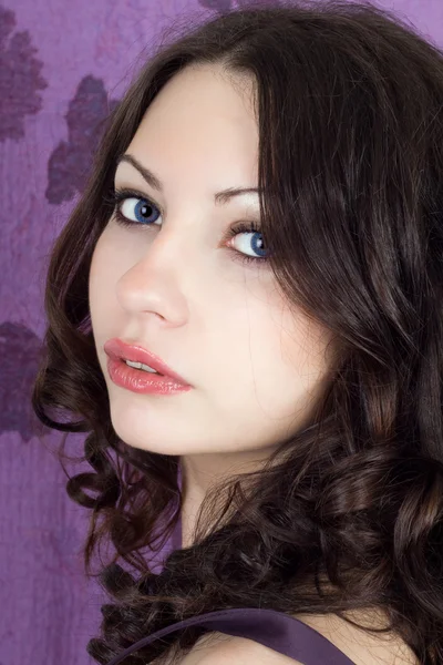 Porträtt av den vackra flickan på en lila bakgrund — Stockfoto