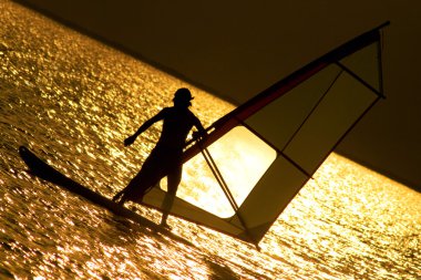 Silhouettes of windsurfer at the evening glow clipart