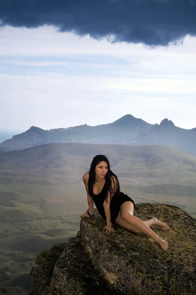 年轻漂亮的女人坐在石头上 — 图库照片