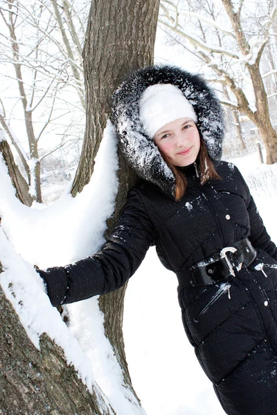 Όμορφο κορίτσι κοντά σε ένα δέντρο στο χιόνι. — Φωτογραφία Αρχείου