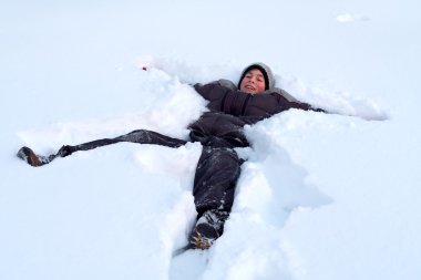 Happy Boy Laying In Fresh Snow clipart