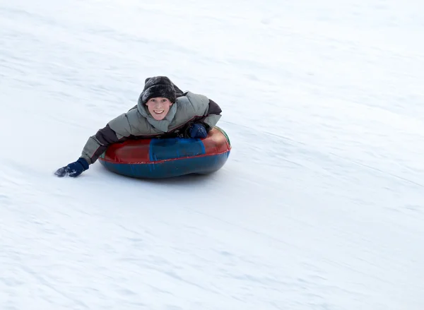 Junge Schlitten Einen Verschneiten Hügel Hinunter Auf Einem Farbigen Aufblasbaren — Stockfoto