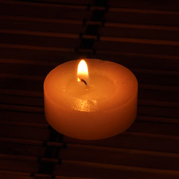 Uma vela conflagrante está na escuridão — Fotografia de Stock