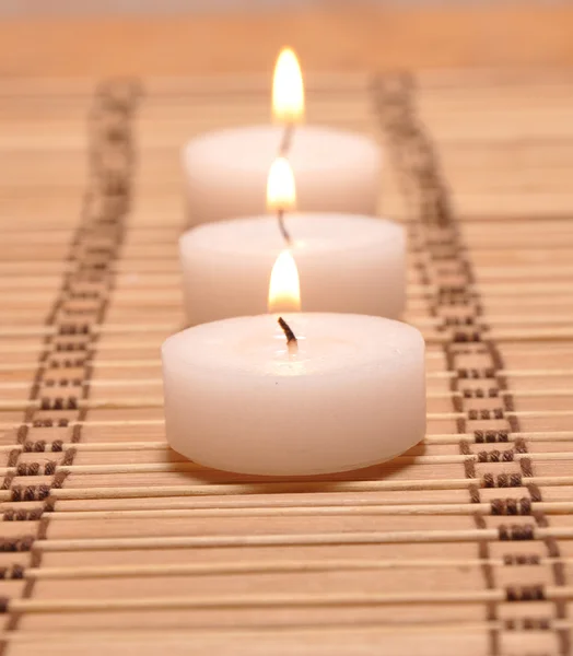 Три свечи на бамбуковом ковре — стоковое фото