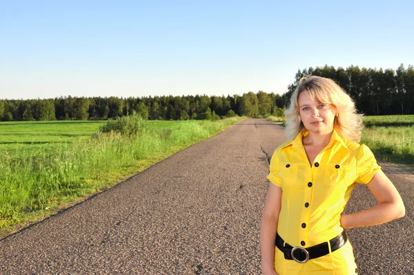 Jovem mulher sorridente com na estrada vazia — Fotografia de Stock