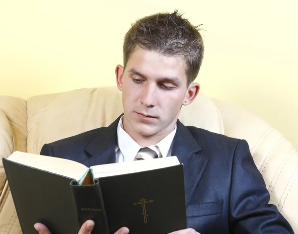 Young guy in a suit reads the Bible — Stock Photo, Image