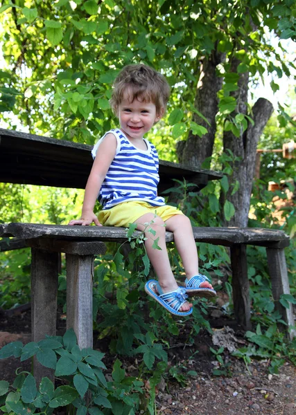 Bambino felice seduto in giardino — Foto Stock