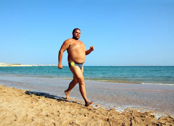 Overweight man running on beach — Stock Photo, Image