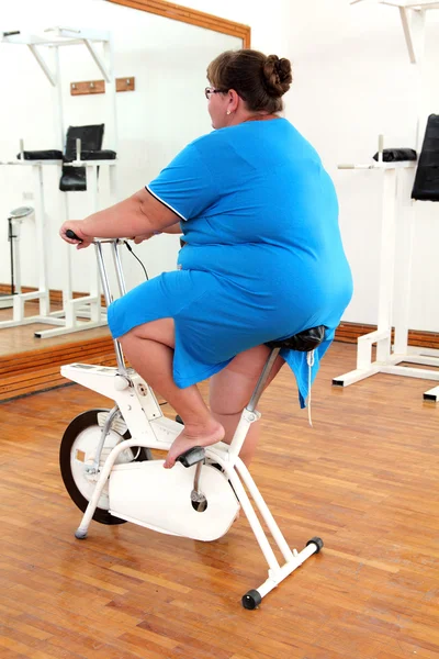 Übergewichtige Frau trainiert auf dem Fahrrad — Stockfoto