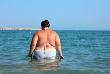 Overweight woman bath in sea clipart