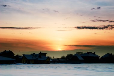 Güneş batmadan ve kar altında evleri ile kırsal kış manzara.