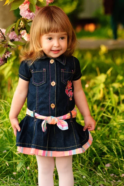 庭桜の木の下で小さな女の子 春の花びらの雨 — ストック写真