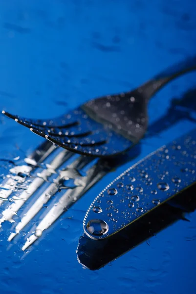 Tenedor y cuchillo bajo el agua azul — Foto de Stock