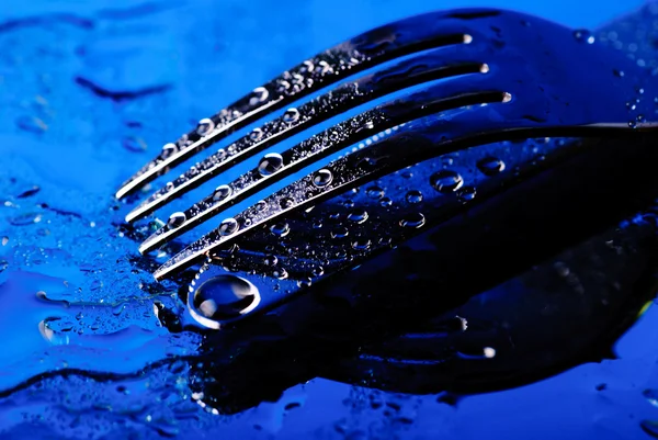 Garfo e faca sob a água azul — Fotografia de Stock
