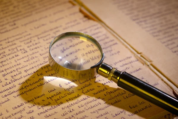 Magnifier glass on page of ancient manuscript — Stock Photo, Image