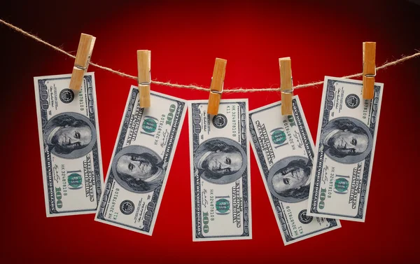 stock image US Dollars Hanging on Rope with Clothespins on red background