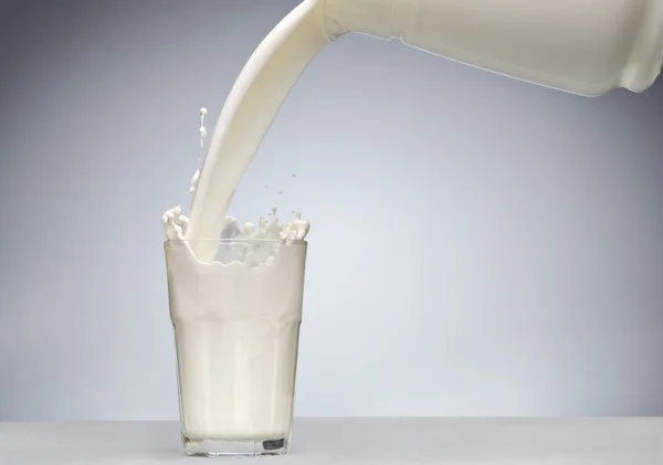 Verter un vaso de leche con salpicadura —  Fotos de Stock