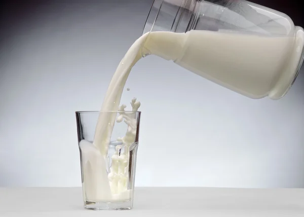 Verter un vaso de leche con salpicadura —  Fotos de Stock