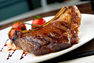 Grilled meat ribs on white plate with tomatoes clipart