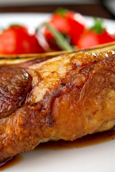 Macro de costillas de carne a la parrilla en plato blanco con tomates —  Fotos de Stock