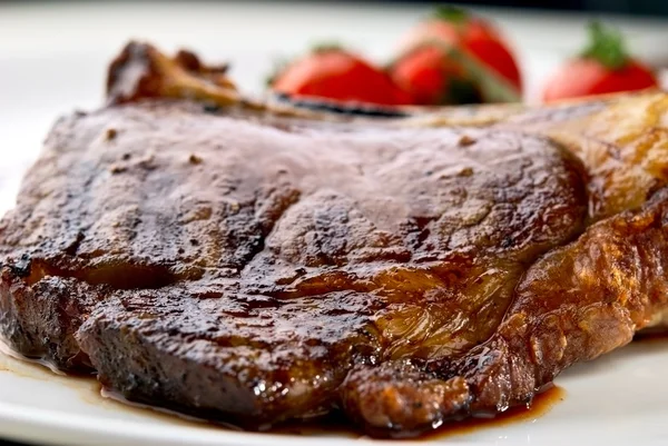 Macro van gegrild vlees ribben op wit bord met tomaten — Stockfoto