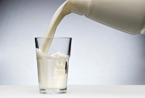 Wylewanie szklankę mleka z splash — Zdjęcie stockowe