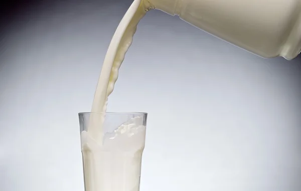 Gießen Sie ein Glas Milch mit Spritzer — Stockfoto