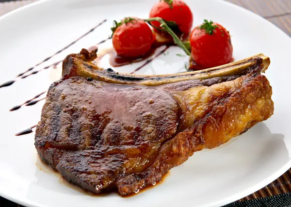 Gegrild vlees ribben op wit bord met tomaten Stockfoto