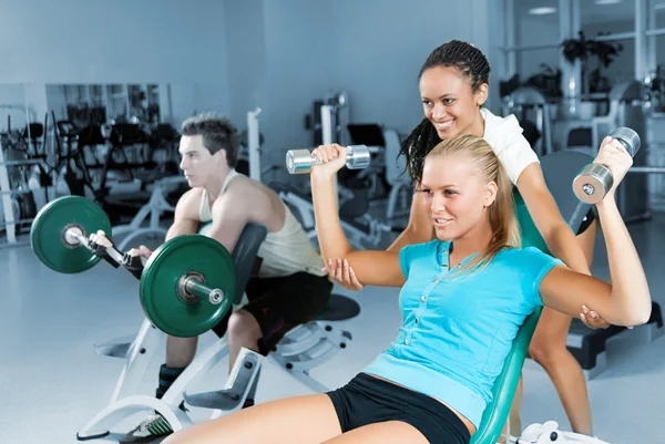Young women lifting a dumb-bell with her trainer Stock Image