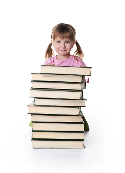 Nettes kleines Mädchen sitzt neben einem Stapel großer Bücher — Stockfoto