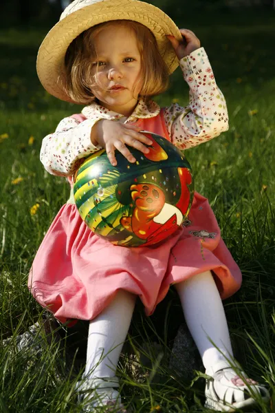 Маленькая девочка в соломенной шляпе с мячом — стоковое фото