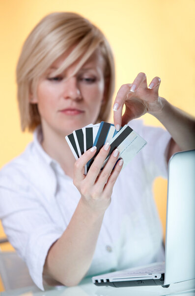 Young woman choosing between five different cards for online payment