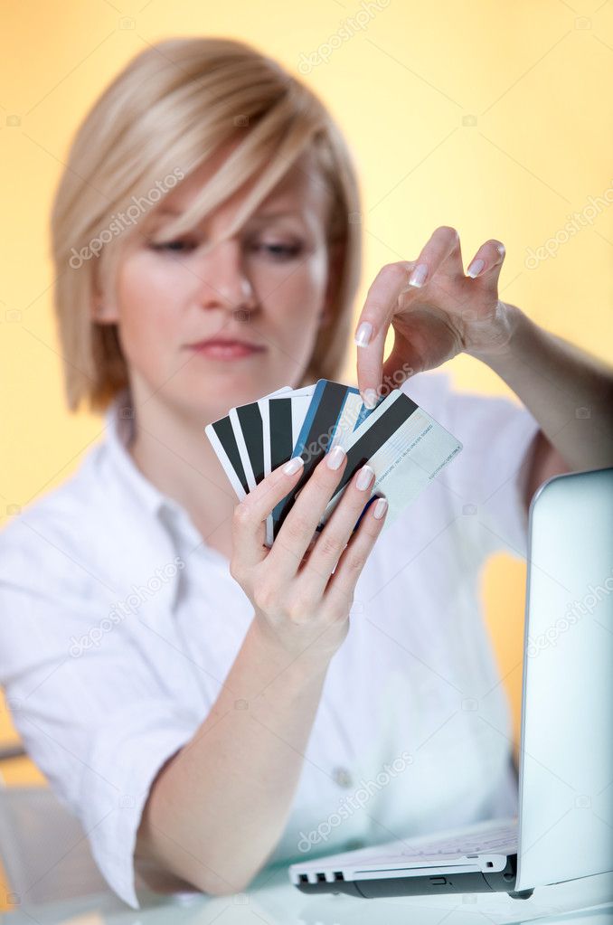 Young woman choosing between five different cards for online payment
