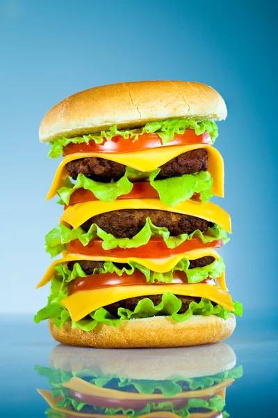 Smakelijke en smakelijk hamburger op een blauw — Stockfoto